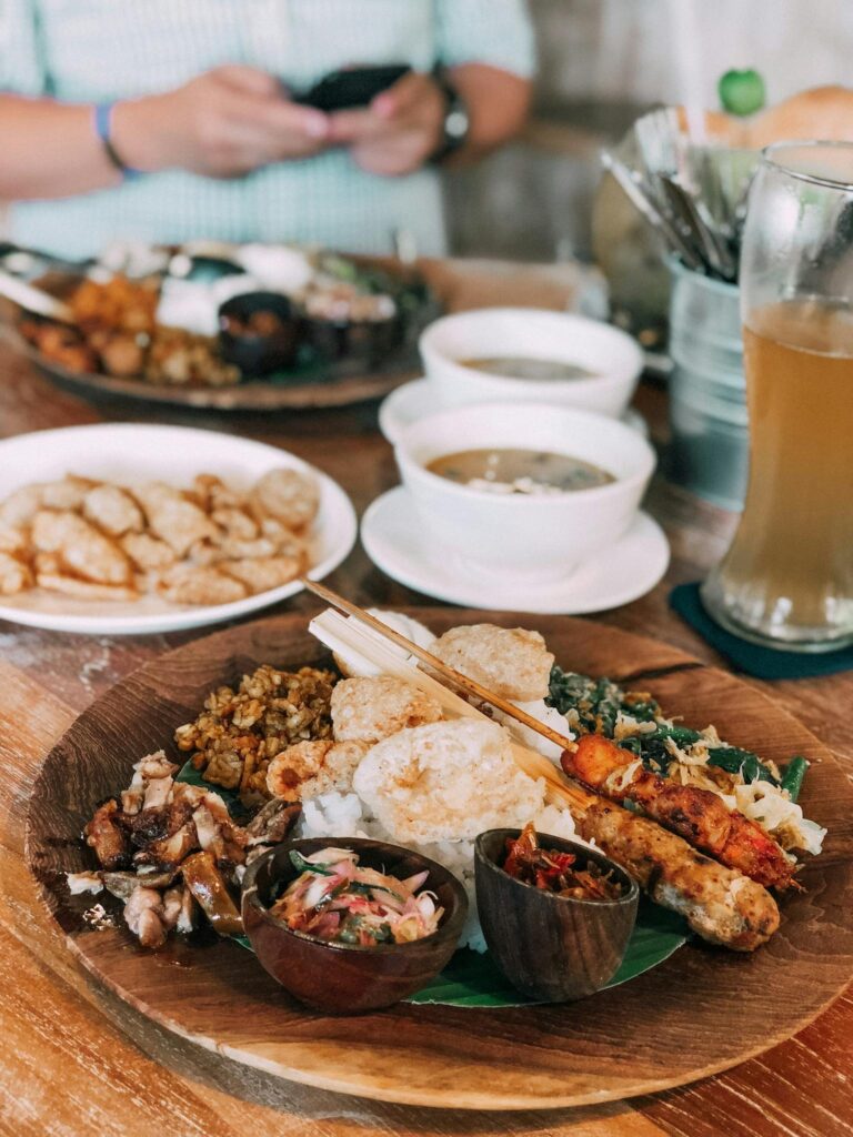 A delicious variety of authentic Indonesian dishes served on a wooden plate with sides and soup.